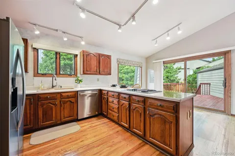 a kitchen with stainless steel appliances granite countertop a sink dishwasher and a refrigerator with wooden cabinets