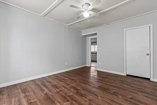 an empty room with wooden floor fan and windows