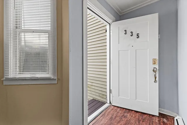 a view of hallway with window and wooden floor