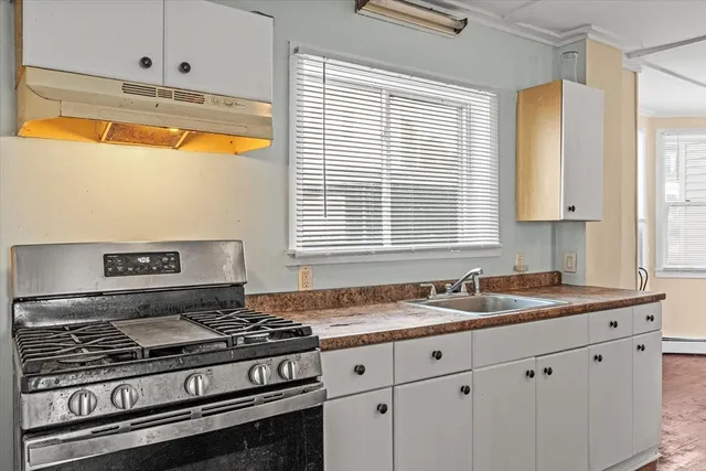 a kitchen with granite countertop a stove a sink and a window