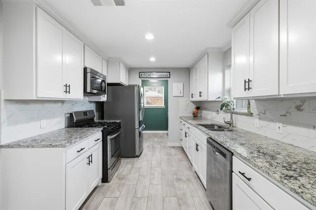 a kitchen with stainless steel appliances granite countertop a stove a sink and a refrigerator