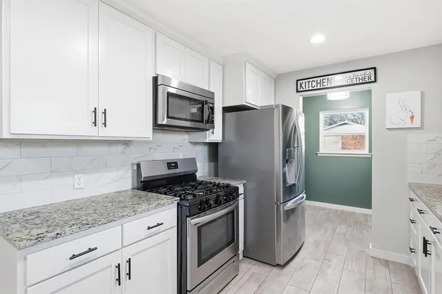a kitchen with granite countertop a refrigerator stove and microwave