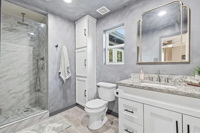 a bathroom with a granite countertop sink toilet and shower