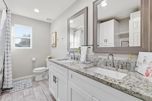 a bathroom with a granite countertop sink mirror vanity and toilet