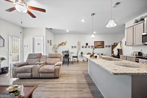 a living room with furniture kitchen view and a wooden floor