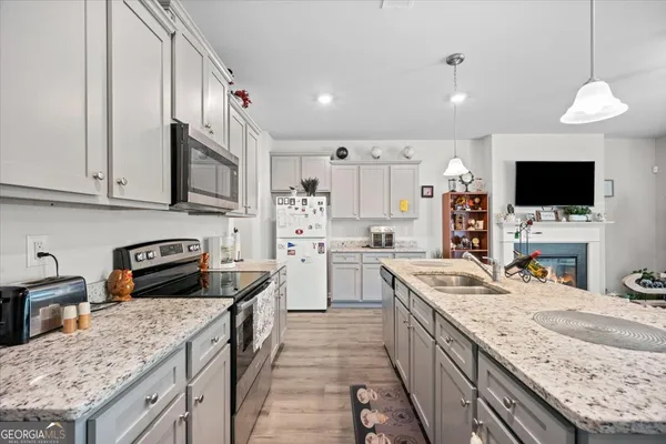 a kitchen with granite countertop a sink a counter top space appliances and cabinets