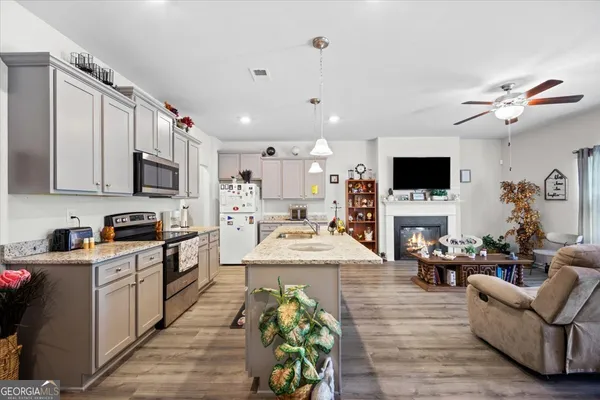 a large living room with stainless steel appliances furniture a fireplace and a flat screen tv