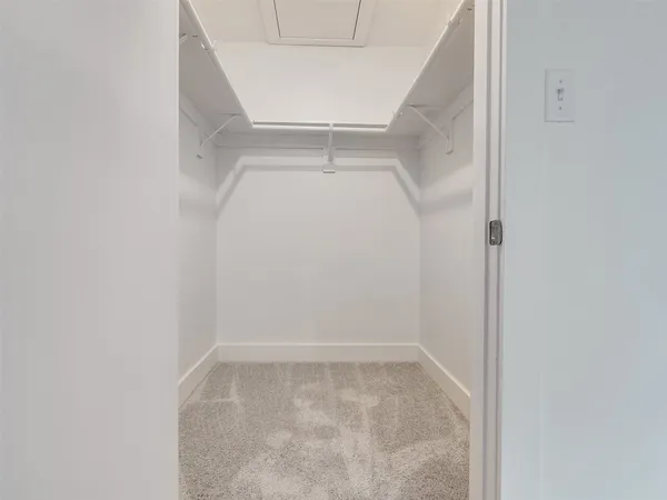 a view of a hallway with wooden floor and a bathroom