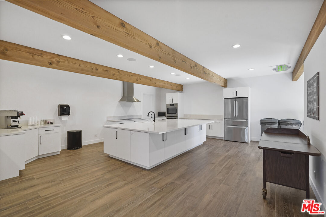 29500 Heathercliff Road, Unit 220 Malibu, CA 90265 - Photo 40 of 43 a kitchen with stainless steel appliances white cabinets and wooden floor