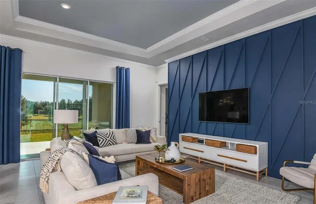 a living room with furniture a flat screen tv and a floor to ceiling window