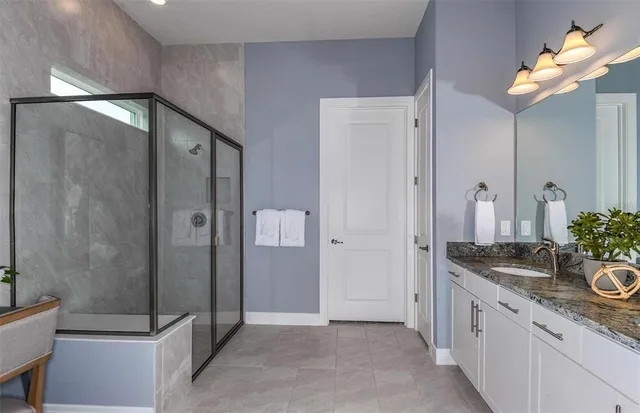 a spacious bathroom with a granite countertop sink a mirror and shower