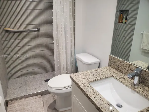 a bathroom with a granite countertop toilet a sink and a shower