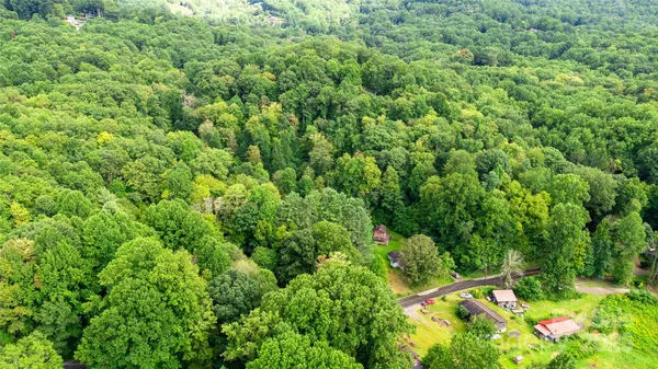an aerial view of residential house with outdoor space and trees all around