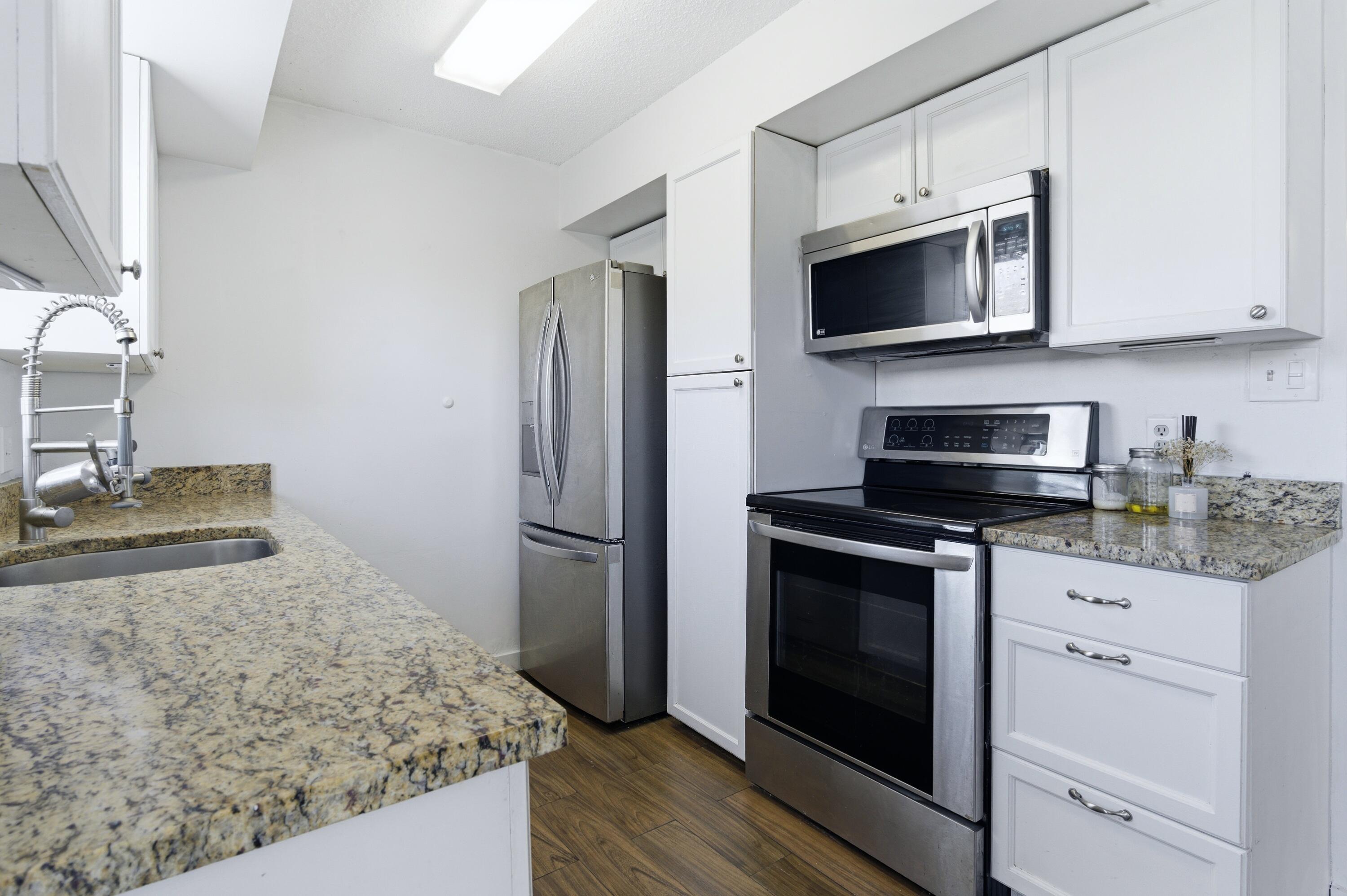 6088 Heather Street Jupiter, FL 33458 - Photo 8 of 18 a kitchen with granite countertop white cabinets and stainless steel appliances