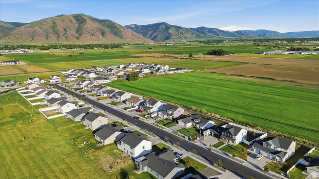1422 West 3410th Street South Logan, UT 84321 - Photo 32 of 33 Aerial perspective showcasing a residential development with mountain backdrops and expansive green fields
