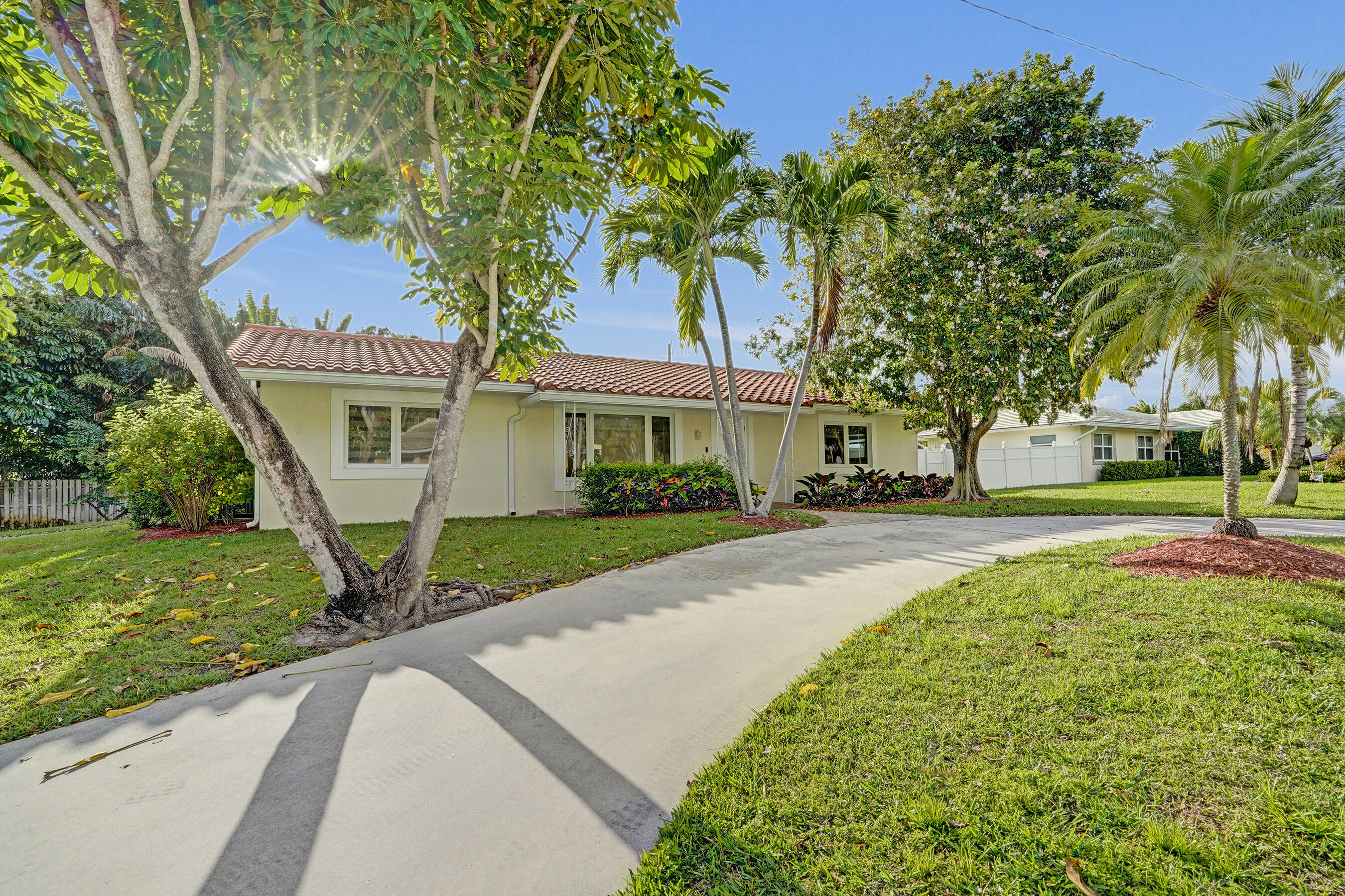 3779 Northwest 4th Court Boca Raton, FL 33431 - Photo 20 of 20 a view of a white house with a big yard and potted plants and large trees
