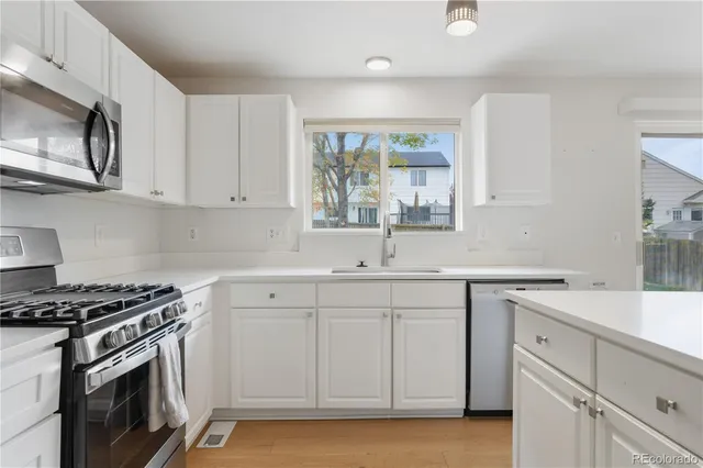 a kitchen with white cabinets stainless steel appliances and sink