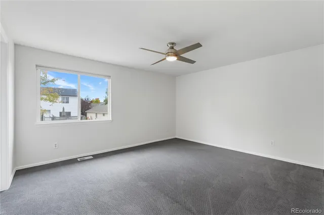 an empty room with a window and ceiling fan