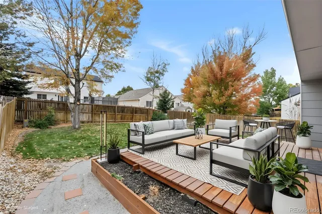 a view of a backyard with couches potted plants and large tree