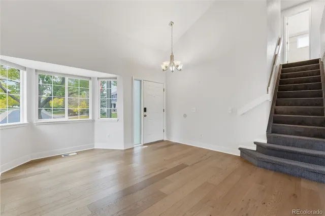 a view of an empty room with wooden floor and windows