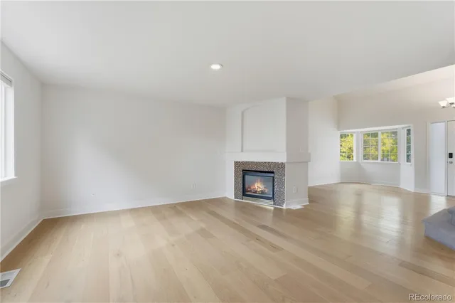 an empty room with wooden floor fireplace and windows