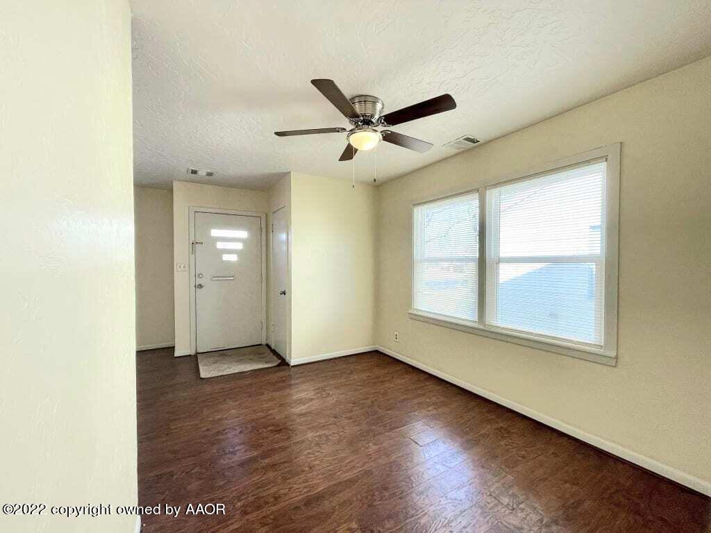 4319 Gables Street Amarillo, TX 79110 - Photo 13 of 15 an empty room with wooden floor ceiling fan and windows