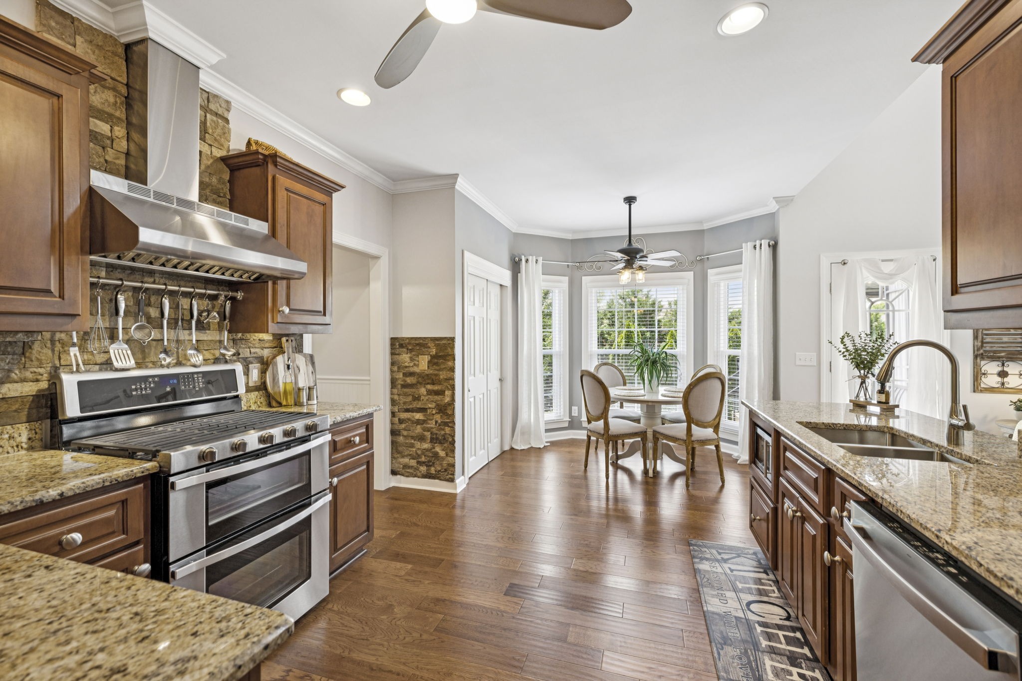 1011 Red Pepper Ridge Spring Hill, TN 37174 - Photo 31 of 76 a kitchen with stainless steel appliances granite countertop a stove top oven a sink a dining table and chairs with wooden floor