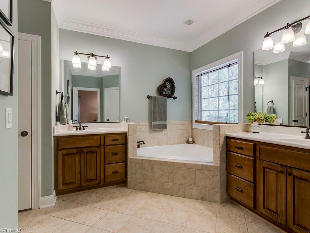 7070 Lanier Road Summerfield, NC 27358 - Photo 16 of 27 Master Bathroom with split, raised vanities and jetted bathtub with tiled surround. Linen closet and private water closet.