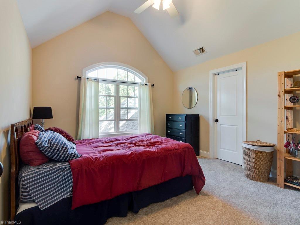 7070 Lanier Road Summerfield, NC 27358 - Photo 20 of 27 Second Bedroom is vaulted with a lake view through the Palladian window. Eave storage and walk-in closet