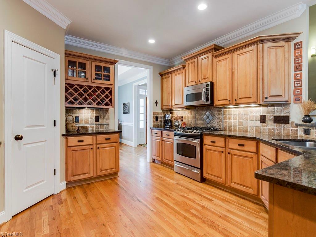 7070 Lanier Road Summerfield, NC 27358 - Photo 9 of 27 Glass-front cabinetry, wine rack and pantry with automatic lighting