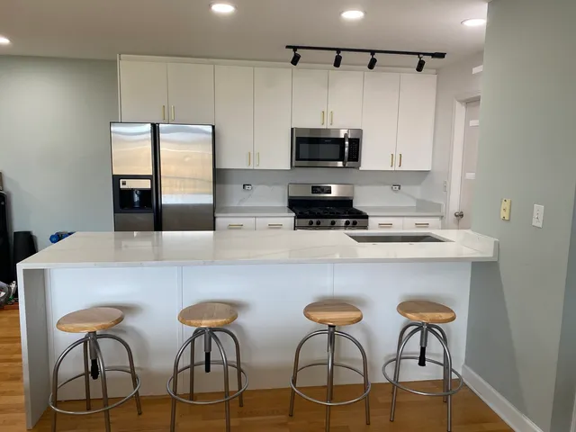 a kitchen with stainless steel appliances a counter space cabinets and chairs