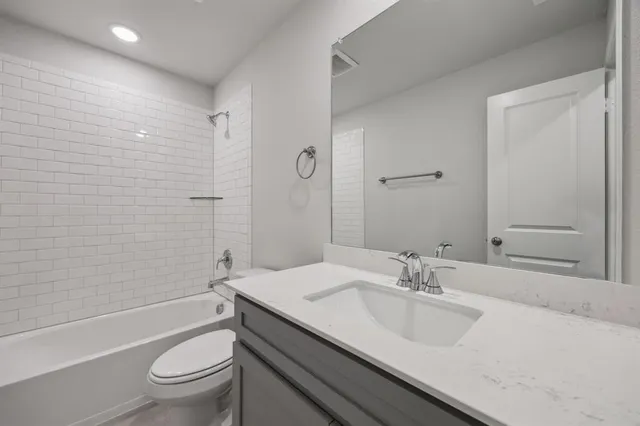 a bathroom with a granite countertop sink a toilet and shower