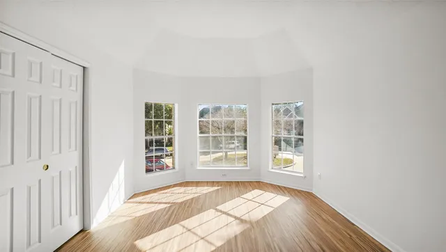 a view of an empty room with wooden floor and a window