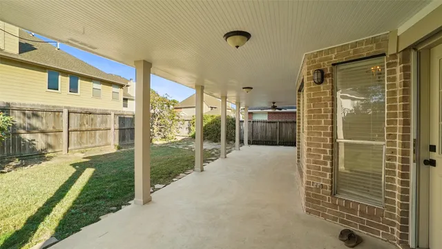 a view of an empty room and window with a ceiling fan