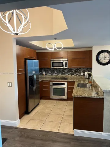 a kitchen with stainless steel appliances granite countertop a stove a sink and a microwave