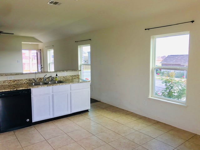 20105 Grover Cleveland Way Manor, TX 78653 - Photo 12 of 17 Granite counters and pristine white cabinetry define this well-appointed kitchen, ideal for daily living.