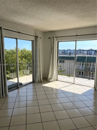 a view of an empty room with a floor to ceiling window and a flat screen tv