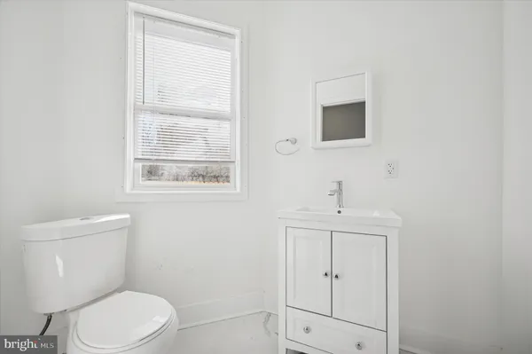 a bathroom with a toilet a sink a window and mirror