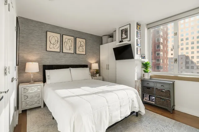 a bedroom with a bed and a flat tv screen on dresser