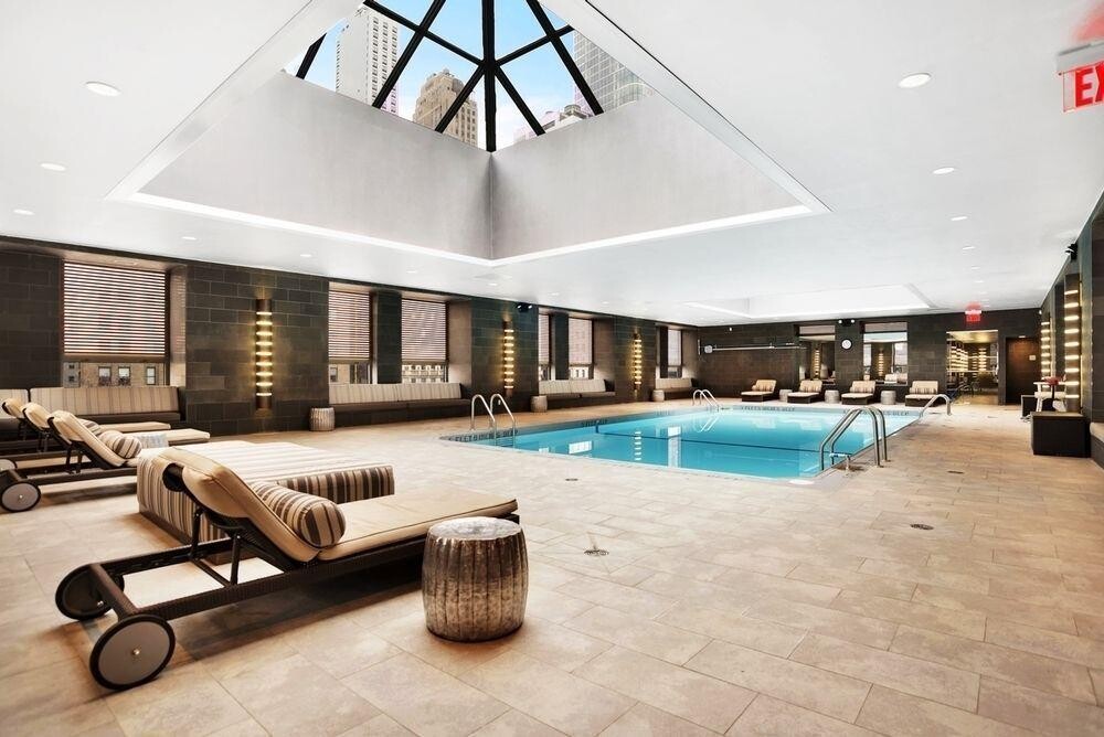 225 Rector Place, Unit 9B Manhattan, NY 10280 - Photo 7 of 14 a living room with furniture a flat screen tv and a large window