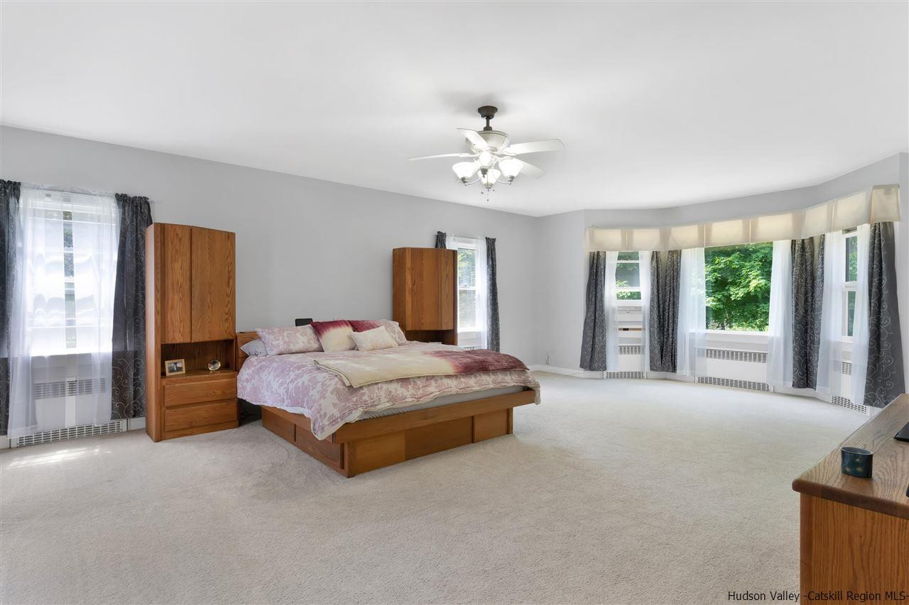 295 Game Farm Road Catskill, NY 12414 - Photo 16 of 35 a spacious bedroom with a large bed and a chandelier