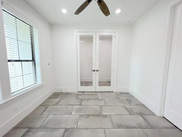 an empty room with windows and ceiling fan
