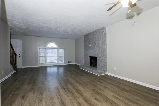 an empty room with wooden floor fireplace and windows
