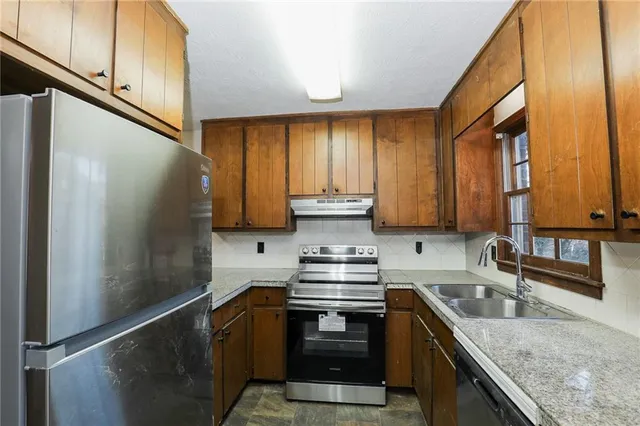a kitchen with stainless steel appliances granite countertop a sink a stove and a refrigerator
