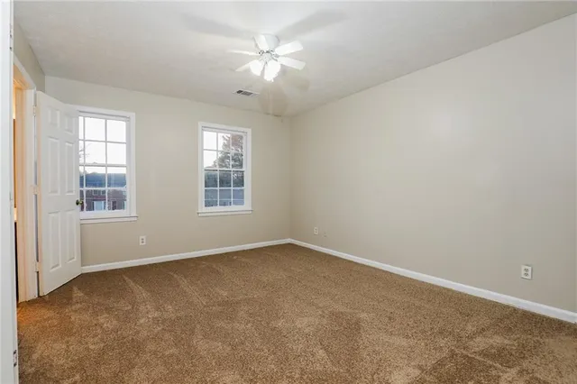 an empty room with windows and fan