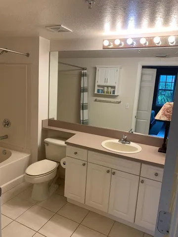 a bathroom with a granite countertop toilet a sink and a mirror