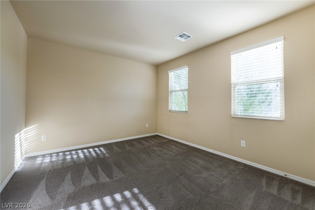 11016 Prairie Grove Road Las Vegas, NV 89179 - Photo 28 of 37 Comfortable carpeted bedroom with natural light flowing through two windows.