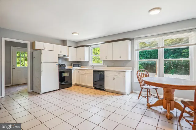 a kitchen with a refrigerator a stove a sink and a dining table with wooden floor