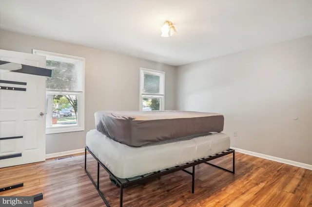 a bedroom with a bed window and wooden floor