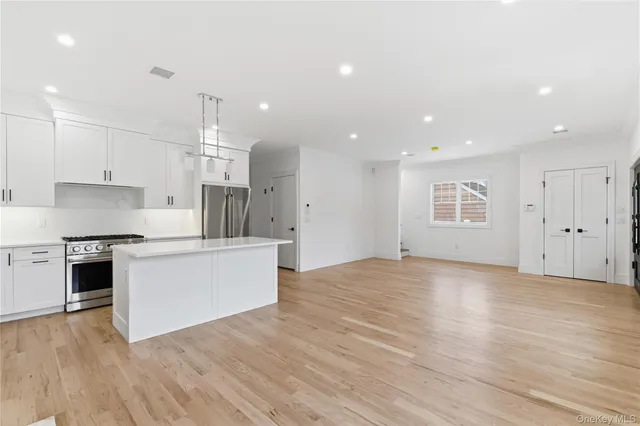a kitchen with stainless steel appliances a refrigerator sink and white cabinets